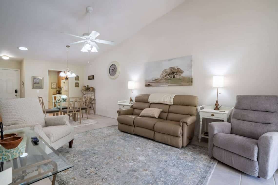 The living and dining space at The Cottage: recliners and a sofa under a vaulted ceiling, the dining table and kitchen beyond.